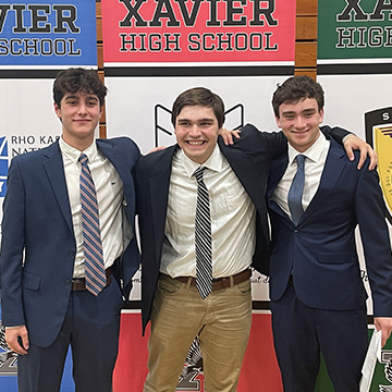Three students in suits with arms around each other