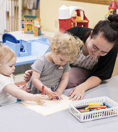 Teacher helps students color with crayons