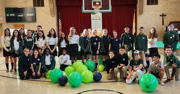 Students lined up in the gym with large green balloons in front of them
