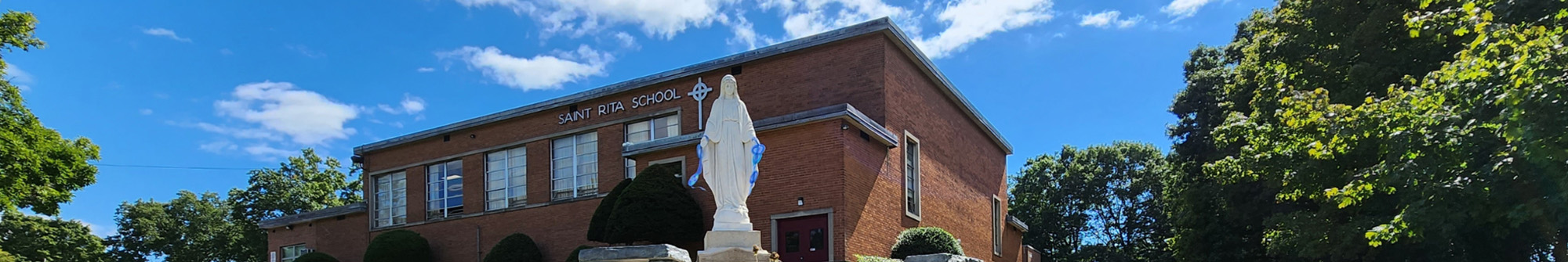 school building with Mary statue in foreground