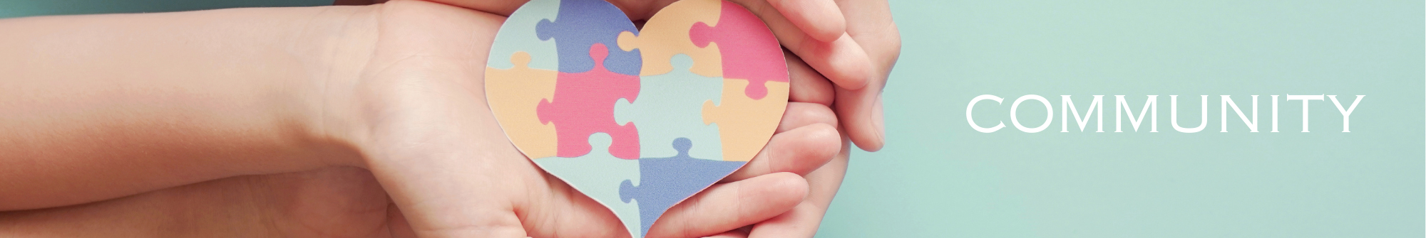 Hands holding heart-shaped puzzle with the word Community
