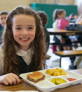 Smiling student sits with her lunch on the table