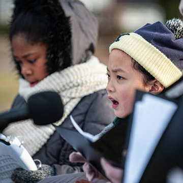 Young girls bundled up and singing outside 